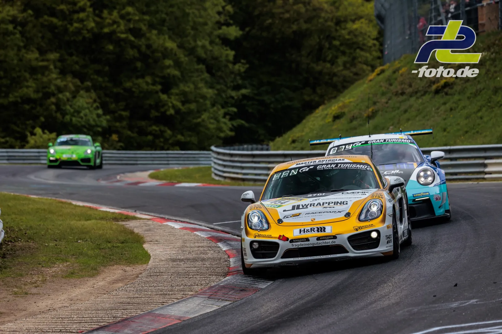 Porsche Cayman CM12* #454 vom Team RSG SH e.V. in Kurve auf der Nordschleife beim 24h-Rennen Nürburgring, gefolgt von zwei weiteren Fahrzeugen.