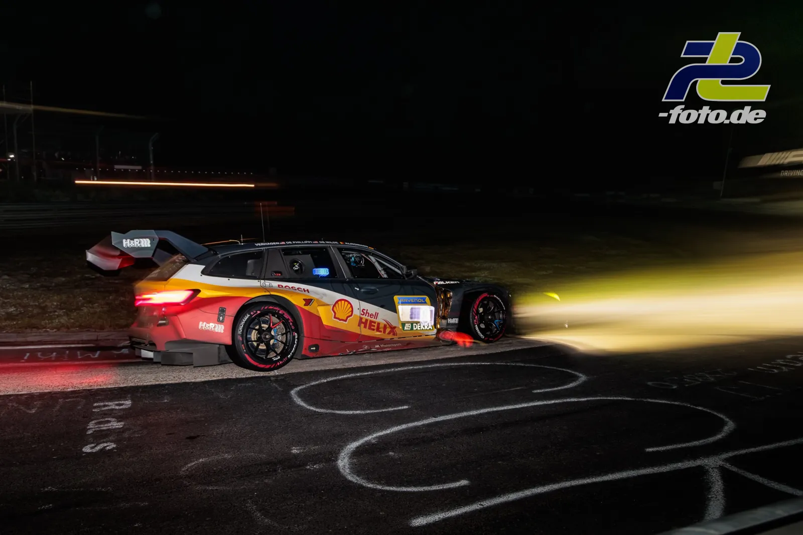 BMW M3 Touring bei Nacht auf dem Nürburgring, beleuchtet von Scheinwerfern eines nachfolgenden Fahrzeugs während des 24-Stunden-Rennens.