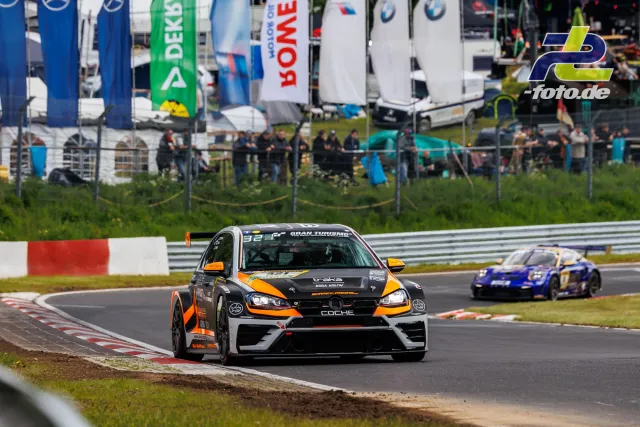 Rennwagen auf der Nordschleife vor Zuschauern und Werbebannern während des Qualifyings zum 24h-Rennen am Nürburgring.