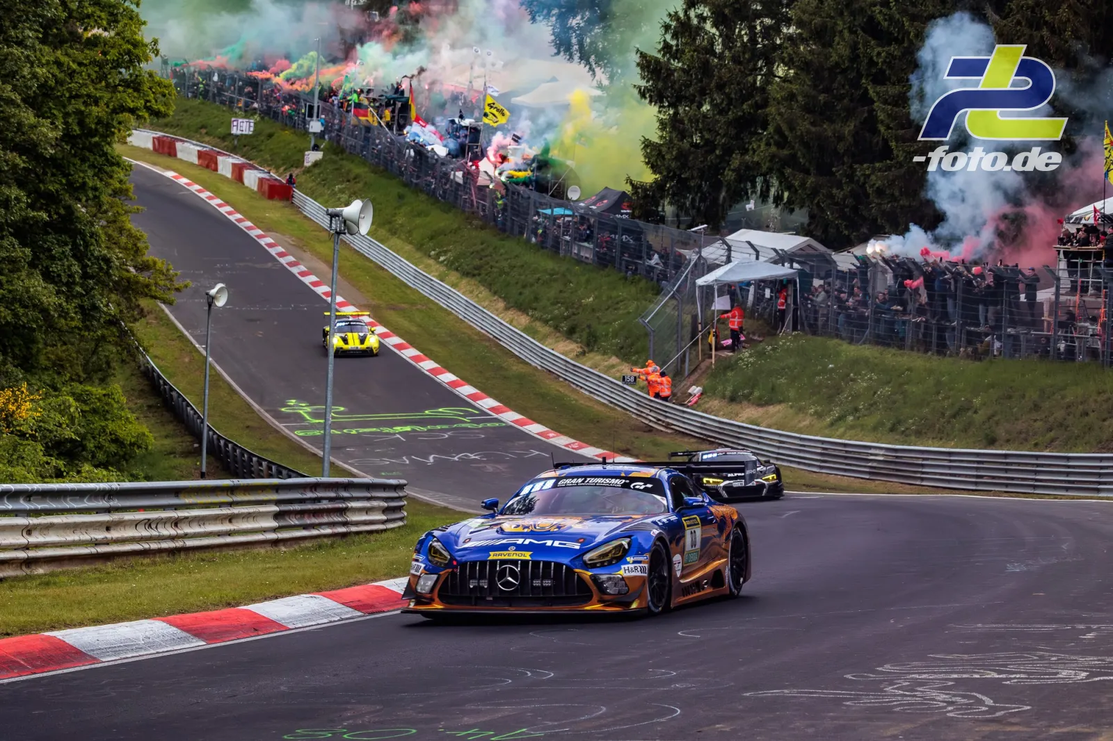 Mercedes-AMG GT3 auf der Nordschleife während der Formationsrunde vor dem 24h-Rennen mit Fans und Rauchfackeln am Streckenrand.