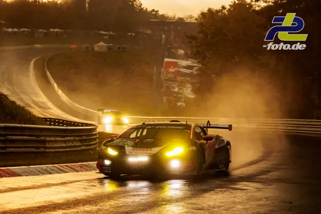 GT3-Rennwagen bei Nässe in der Dämmerung mit eingeschalteten Scheinwerfern auf der Nordschleife des Nürburgrings