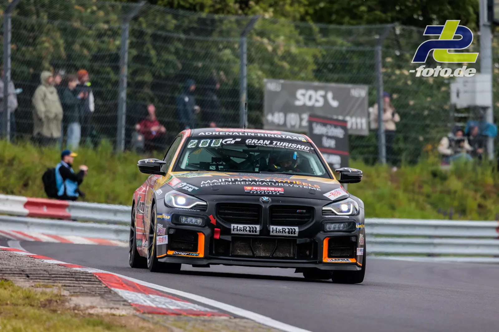 BMW M2 Racing auf der Nordschleife beim 24h-Rennen am Nürburgring, Frontansicht während des Rennens mit Zuschauern im Hintergrund
