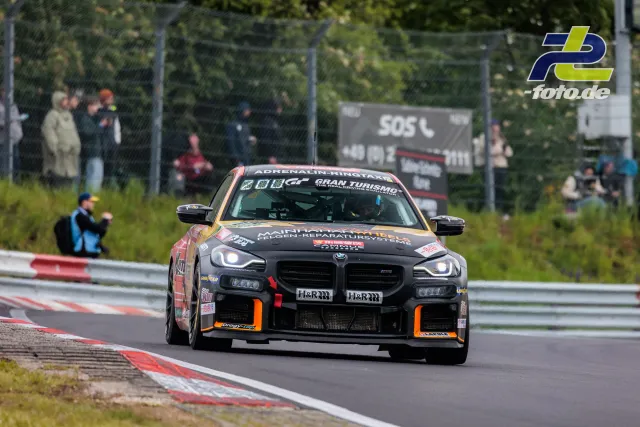 BMW M2 Racing (G87)* in schwarz-orange auf der Nordschleife beim 24h-Rennen, Zuschauer am Streckenrand