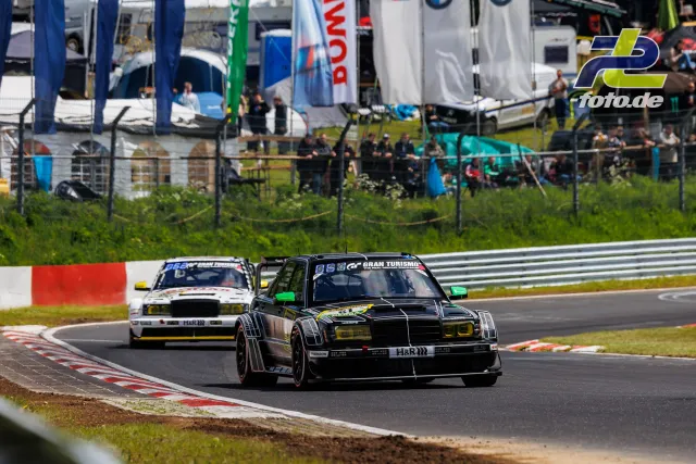 Zwei klassische Rennfahrzeuge mit H&R-Sponsoring in Kurve auf der Nürburgring-Nordschleife während des Qualifyings.