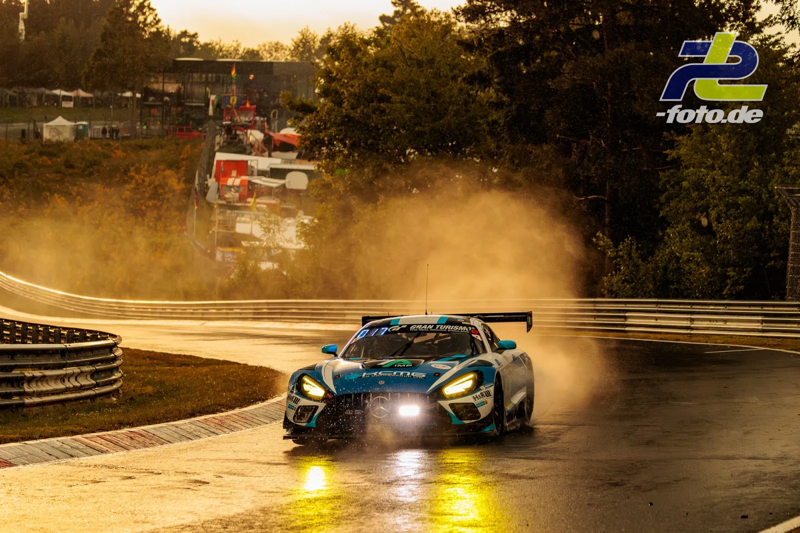 BMW M4 GT3 auf nasser Strecke am Nürburgring, Gischt spritzend bei Qualifying-Fahrt im Gegenlicht.
