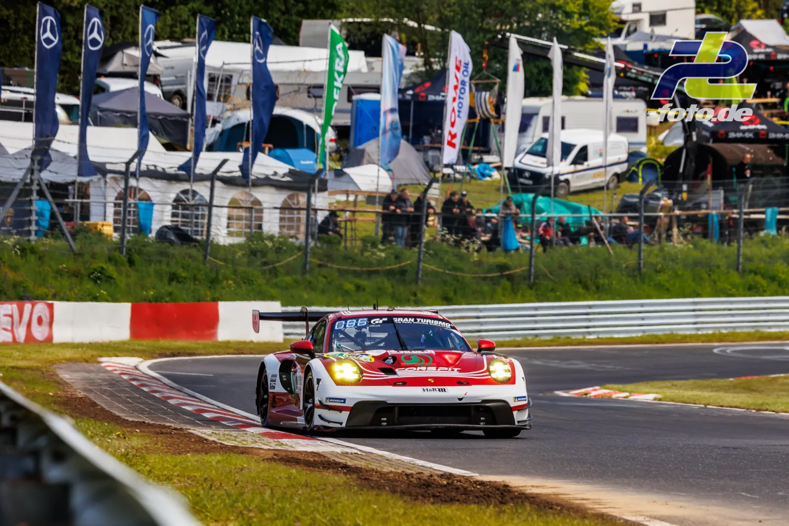 Porsche 911 GT3 R von High Class Racing in Kurve auf der Nordschleife beim Qualifying zum 24h-Rennen Nürburgring, Fahrerlager im Hintergrund.