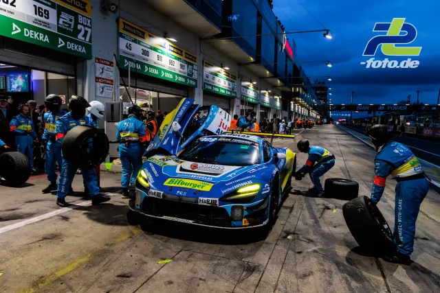 Boxenstopp eines McLaren GT3 während der blauen Stunde beim 24h-Rennen am Nürburgring, Team arbeitet an Reifenwechsel.