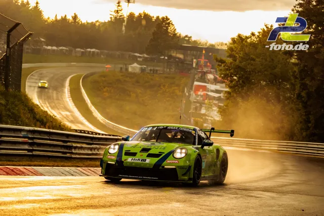 Porsche 911 GT3 R in grüner Lackierung auf nasser Strecke bei Gegenlicht während des Qualifyings zum 24h-Rennen Nürburgring.