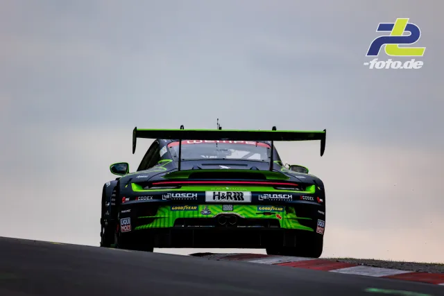 Porsche 911 GT3 R in schwarz-grüner Lackierung von hinten auf Bergkuppe, 24h Nürburgring