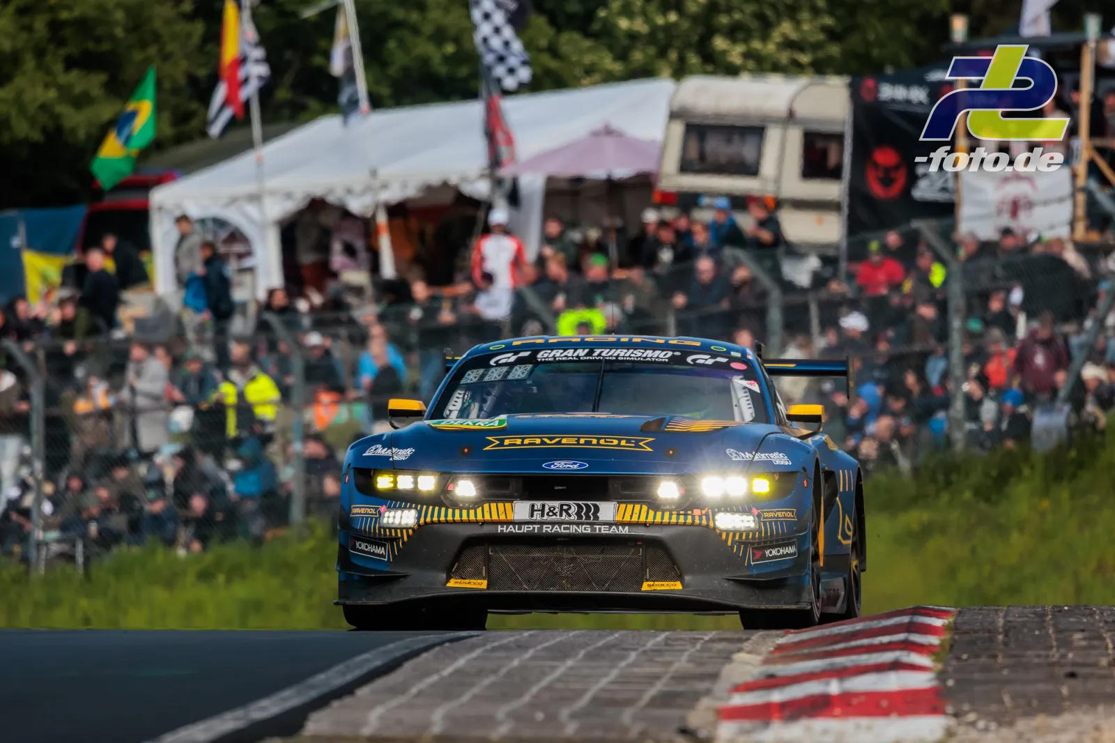 Ford Mustang GT3 EVO in Frontansicht auf dem Nürburgring, Zuschauer und Flaggen im Hintergrund während des 24h-Rennens