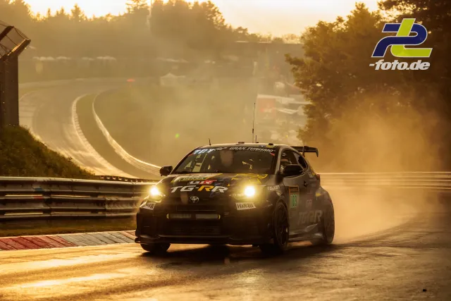 Toyota GR86 in Gegenlicht mit eingeschalteten Scheinwerfern auf der Nordschleife bei tiefstehender Sonne.