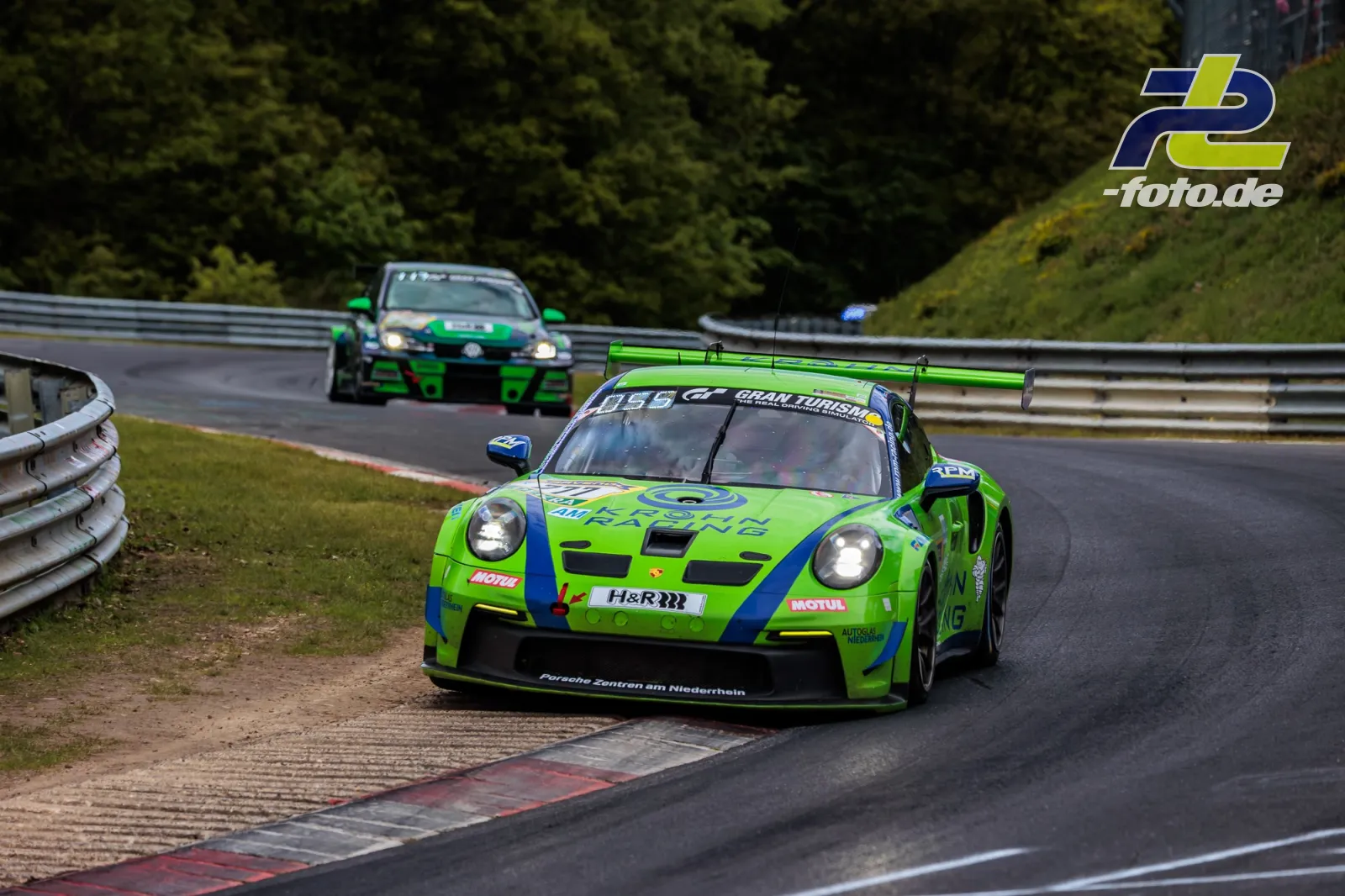 Porsche 911 GT3 Cup in grün-blauer Lackierung beim 24h-Rennen auf der Nürburgring-Nordschleife, gefolgt von weiteren Fahrzeugen.