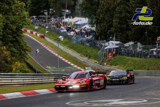 Zwei GT3-Fahrzeuge im Rennbetrieb auf der Nordschleife des Nürburgrings mit Zuschauern und Zelten im Hintergrund