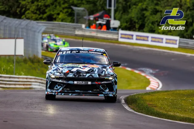 Rennwagen mit markanter schwarz-weiß-roter Tarnlackierung auf der Nordschleife des Nürburgrings beim Qualifying.