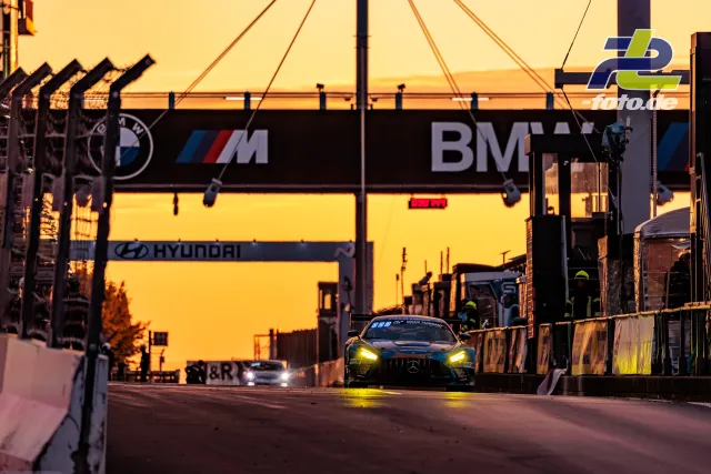 Mercedes-AMG GT3 fährt bei Sonnenuntergang durch die Boxengasse des Nürburgrings während des 24-Stunden-Rennens.