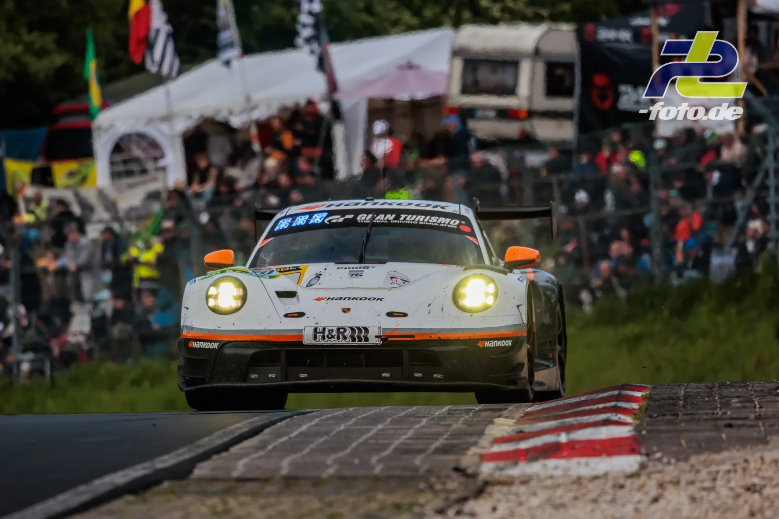 Porsche 911 GT3 R mit Startnummer 30 in weißer Lackierung mit orangenen Akzenten im Rennen auf der Nürburgring-Nordschleife.