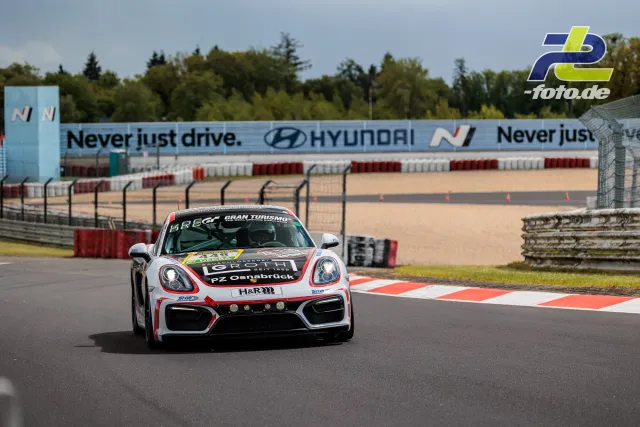 Porsche Cayman GT4 Clubsport in weiß-rot-schwarzer Lackierung auf der Nordschleife beim Qualifying zum 24h-Rennen.