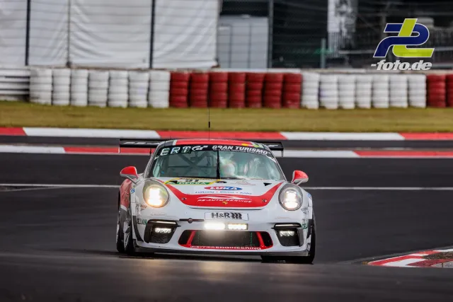 Porsche 911 GT3 Cup mit Startnummer 91 in rot-weißer Lackierung im Qualifying auf dem Nürburgring, Frontansicht mit eingeschalteten Scheinwerfern.