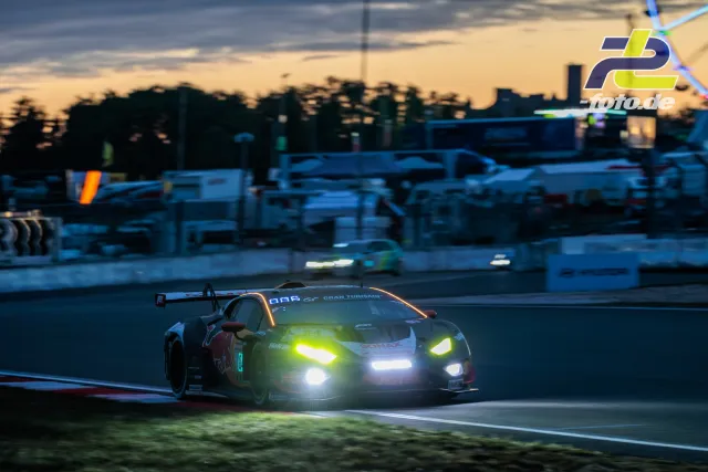 GT3-Rennwagen mit eingeschalteten Scheinwerfern bei Dämmerung auf dem Nürburgring während des 24-Stunden-Rennens.