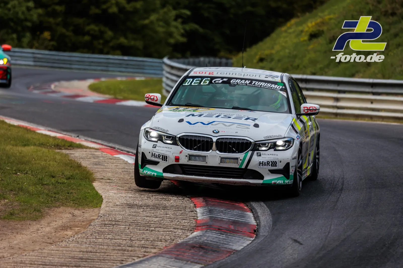 BMW 330i #514 des SRS Team Sorg Rennsport in Kurve beim 24h Nürburgring, über Randsteinen fahrend