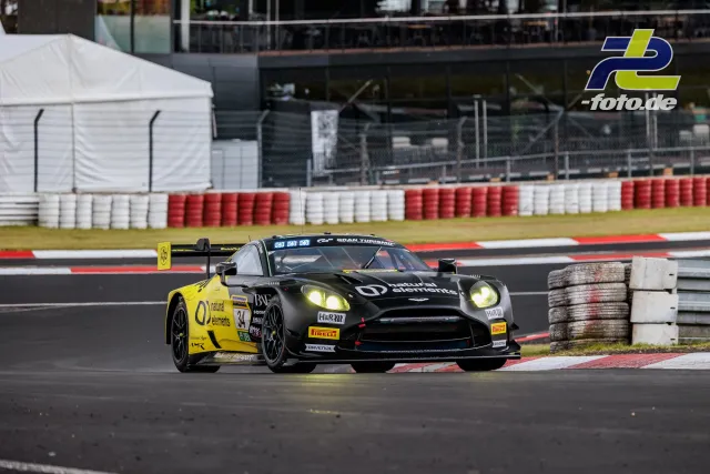 Aston Martin V8 Vantage GT3 mit schwarz-gelber Lackierung in schneller Kurve auf der Nürburgring-Nordschleife während des Qualifyings.