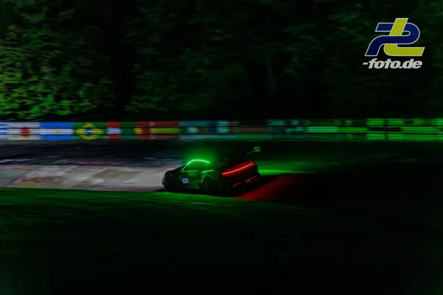 GT3-Sportwagen bei Nachtfahrt am Nürburgring, leuchtend grüne Lackierung mit roten Rückleuchten, Mitzieher.