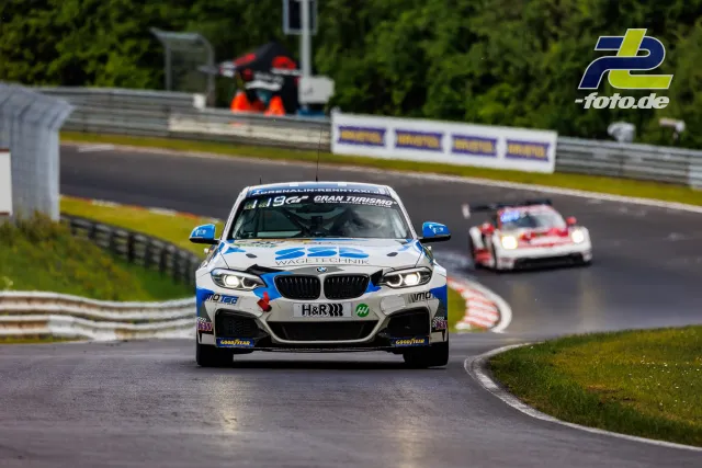 BMW M240i Racing beim Qualifying auf der Nordschleife, gefolgt von einem Porsche, nasse Strecke.