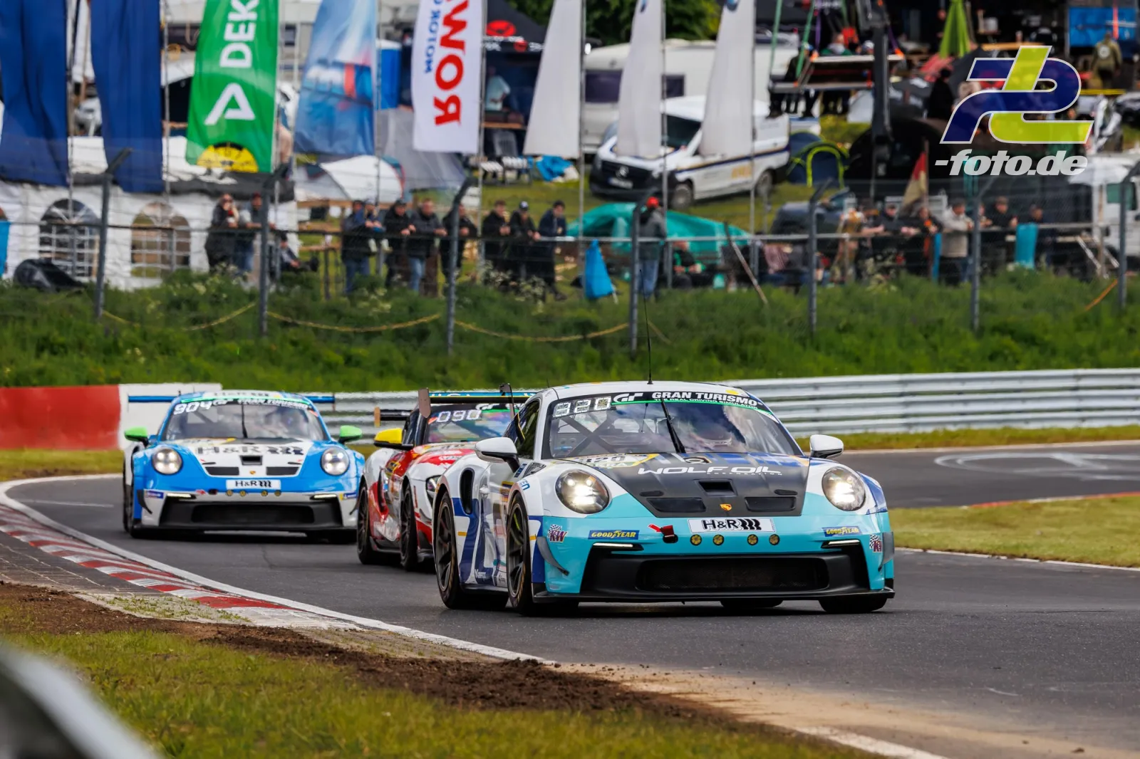 Drei Porsche 911 GT3 R im Qualifying auf dem Nürburgring, führender Wagen #920 in hellblau mit schwarzer Motorhaube, Zuschauer im Hintergrund.