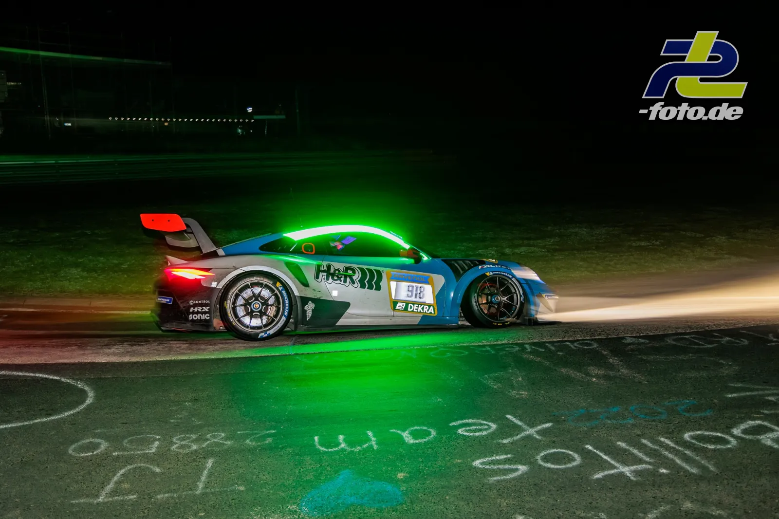 Porsche 911 GT3 R #918 in grün-blau-weißer HER-Lackierung nachts auf der Strecke am Nürburgring während des 24h-Rennens.
