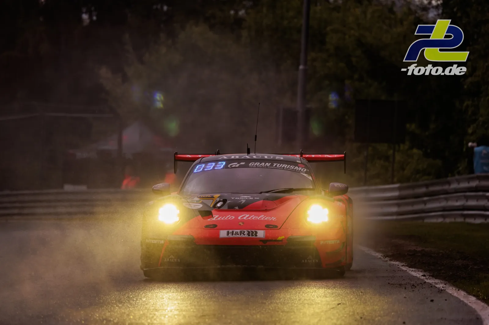 Porsche 911 GT3 R bei Regen auf nasser Strecke während des Qualifyings zum 24h-Rennen am Nürburgring mit eingeschalteten Scheinwerfern.