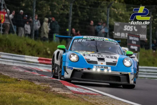 Porsche 911 GT3 R in blau-weißer Lackierung mit grünen Spiegeln auf der Nordschleife beim 24h-Rennen Nürburgring.