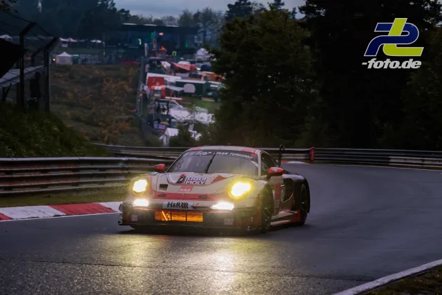 Porsche 911 GT3 R mit Beleuchtung bei Dämmerung auf nasser Nordschleife während des 24h-Rennen Nürburgring Qualifyings.