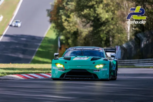 Türkisfarbener Aston Martin Vantage GT3 mit gelben Scheinwerfern auf der Nürburgring-Nordschleife während des Rennens.