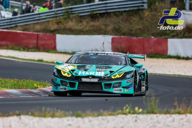 Türkis-grüner Lamborghini Huracán GT3 in Kurve auf der Nordschleife, Zuschauer an Leitplanke im Hintergrund, NLS Rennen.