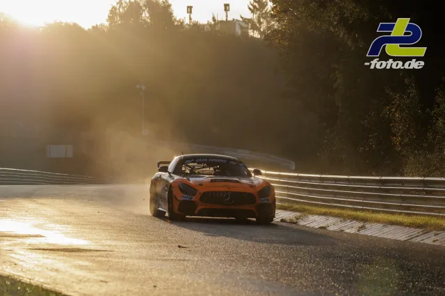 Mercedes-AMG GT in oranger Lackierung bei Gegenlicht auf der Nordschleife, starke Staubentwicklung durch warme Abendsonne