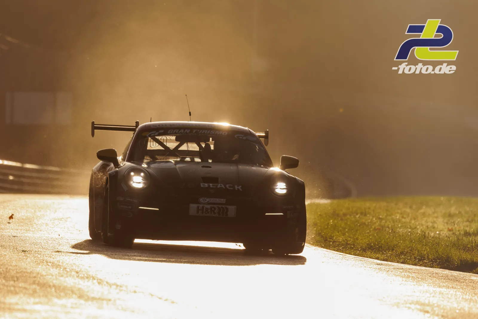 Schwarzer Porsche 911 GT3 Cup im Gegenlicht während des Qualifyings auf dem Nürburgring, Frontansicht mit eingeschalteten Scheinwerfern.