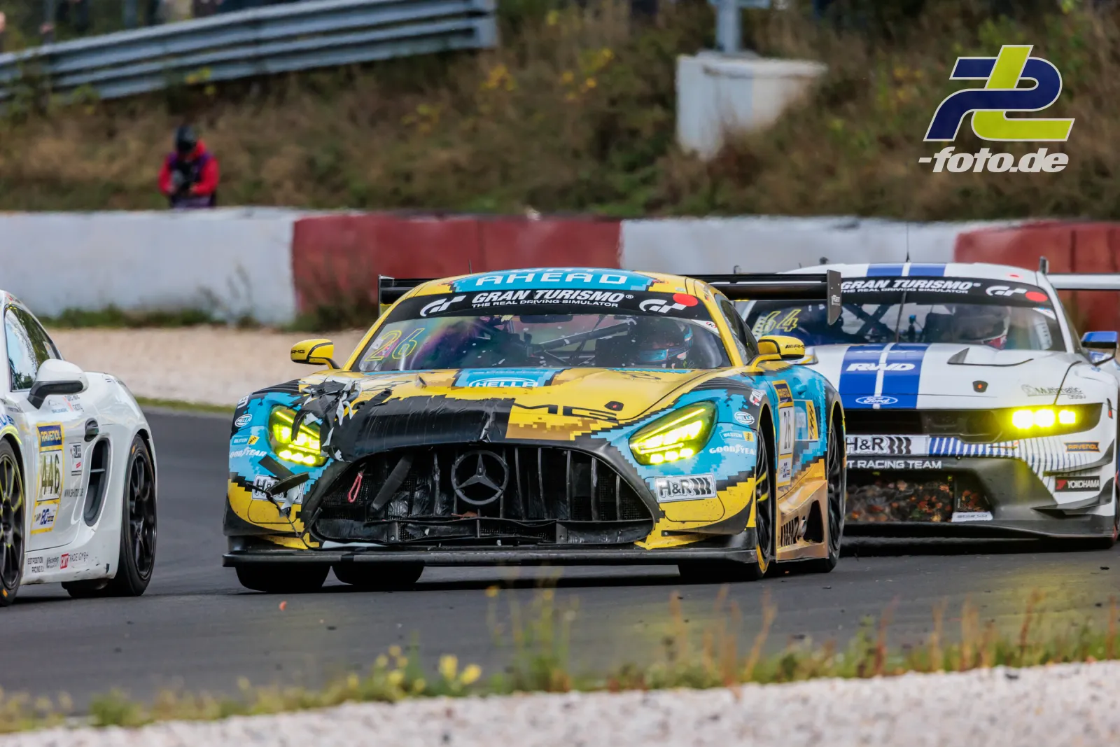 Mehrere GT-Fahrzeuge im Rennen auf dem Nürburgring, angeführt von einem gelb-türkis lackierten Mercedes-AMG GT3 mit Frontschaden.