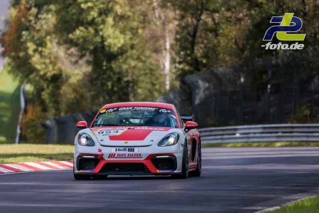 Porsche 718 Cayman GT4 Clubsport in weiß-roter Lackierung auf der Nordschleife während des Rennens.