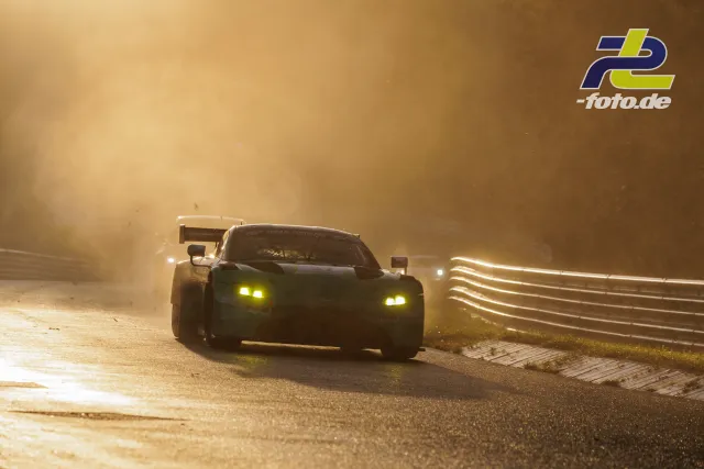 GT-Rennwagen im Gegenlicht auf dem Nürburgring, Staubwolke bei tief stehender Sonne, gelbe Scheinwerfer eingeschaltet.