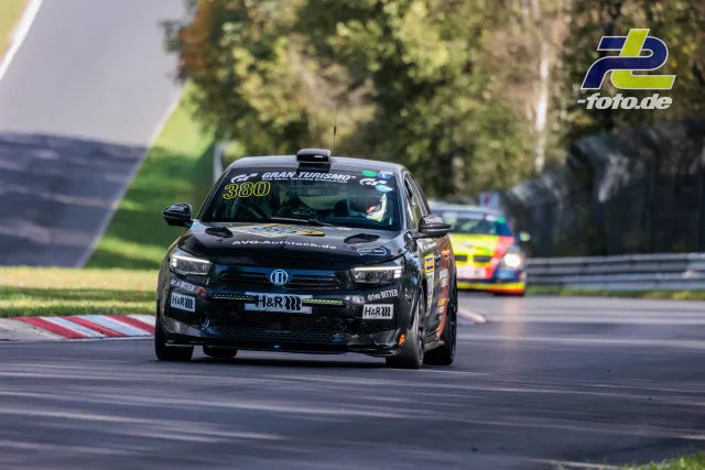Schwarzer Rennwagen mit Startnummer 380 auf der Nordschleife, gefolgt von einem gelb-grünen Fahrzeug.