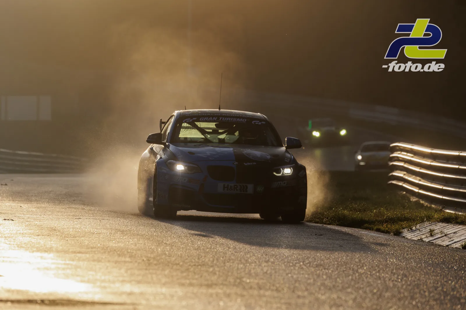 BMW-Rennwagen im Gegenlicht bei nebligem Qualifying auf dem Nürburgring, Leitplanke im Hintergrund
