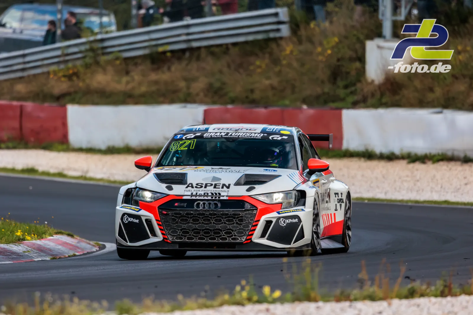 Audi Nummer 821 mit weiß-roter Aspen-Lackierung in einer Kurve auf dem Nürburgring während des NLS-Rennens.