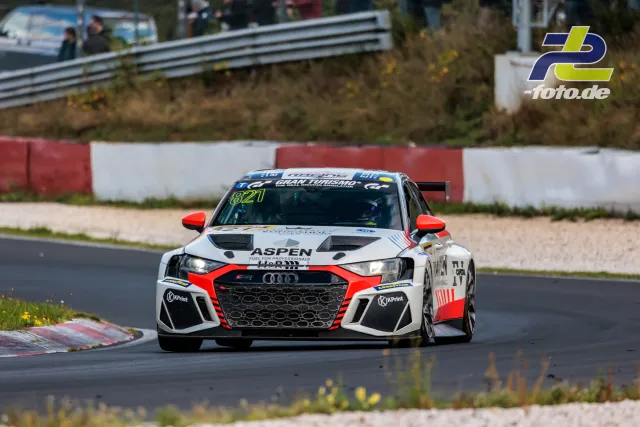 Audi Nummer 821 mit weiß-roter Aspen-Lackierung in einer Kurve auf dem Nürburgring während des NLS-Rennens.