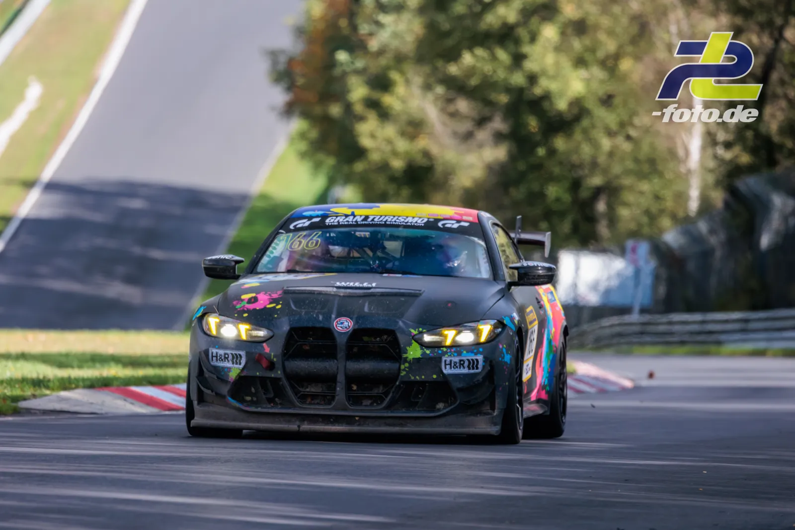 BMW M4 GT4 EVO in bunter Lackierung auf der Rennstrecke am Nürburgring während des NLS-Rennens, Frontansicht.