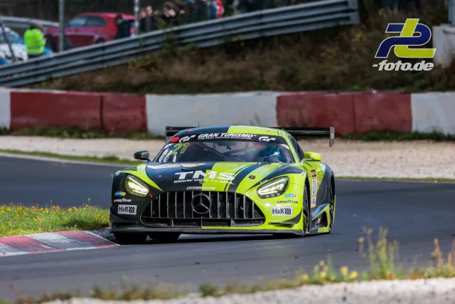 Mercedes-AMG GT3 Nr. 21 in neongelb-blauer Lackierung beim NLS-Rennen auf dem Nürburgring, Kurvenaktion über Randstein.