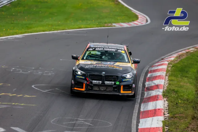 BMW M2 in Kurve auf der Nordschleife beim NLS-Rennen, schwarz-orange Lackierung mit zahlreichen Sponsoren