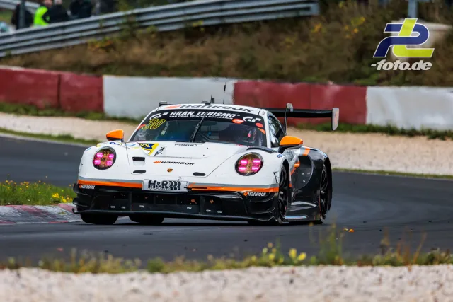 Weißer Porsche 911 GT3 R mit orangenen Akzenten auf der Nordschleife während des Rennens, Startnummer 30