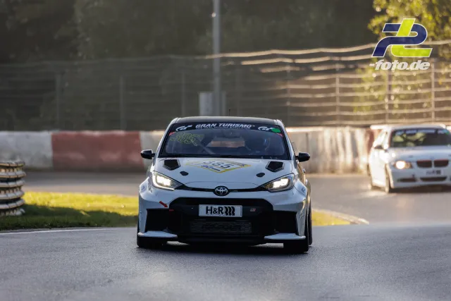 Toyota GR Yaris im Qualifying auf dem Nürburgring, frontale Perspektive, gefolgt von einem BMW, Herbstlicht.