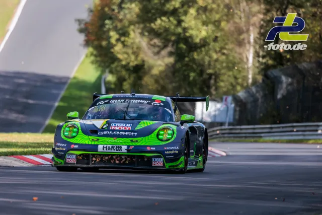 Porsche 911 GT3 R in markanter grün-grauer Lackierung auf der Nürburgring-Nordschleife während des Rennens.