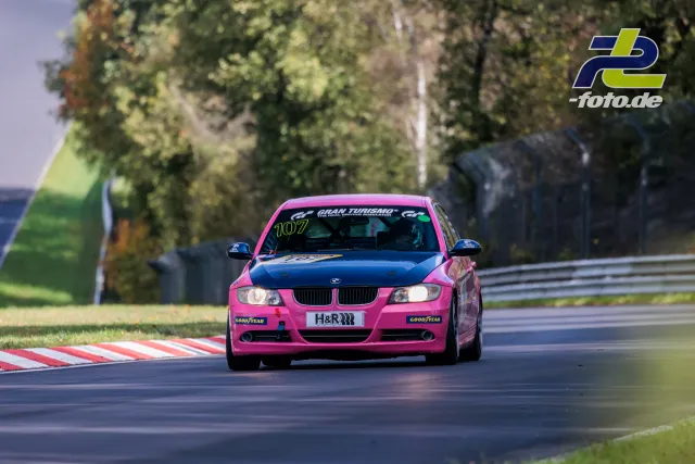 Pink-magenta lackierter BMW mit Startnummer 107 in einer Kurve auf dem Nürburgring bei der NLS Sportwarte-Trophy.
